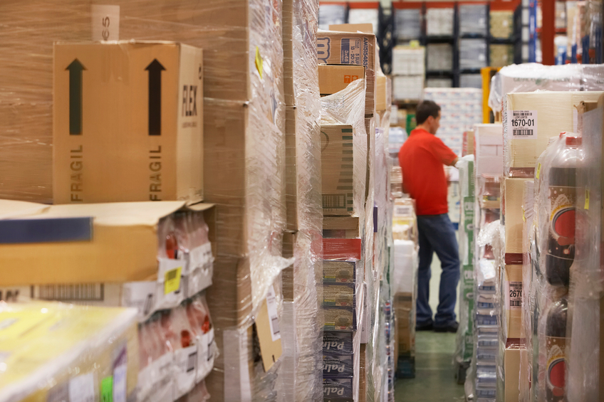 Warehouse full of cellophane wrapped goods with man in the background